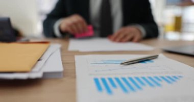 İş yerinde elinde analitik kağıtlarla oturan erkek ofis çalışanı damgaları. Resmi takım elbise yöneticisi yatırımcılara belge hazırlamakta zorlanıyor