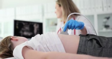 Nazik kadın doktor, ultrason cihazıyla mide hastalığı olan küçük bir kızı muayene ediyor. Dikkatli kadın yavaş çekimde hastanın iç karın görüntüsüne bakıyor.