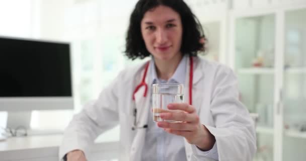 Позитивний Лікар Стетоскопом Дає Склянку Води Пацієнту Який Дивиться Камеру — стокове відео