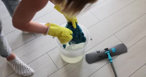 家の湿った掃除の後 洗剤のバケツの中で黄色の手袋リンスモップ布の女性 主婦は家で寄木細工の床をきれいにする — ストック動画