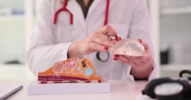 Kadın sıhhiyeci kalemle silikon implantın yapay modelini gösteriyor. Uzman kadın hastalıklarının hafif hastanede ağır çekimde olduğunu açıkladı.