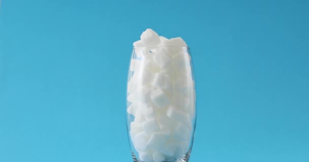 Transparentes Glas Voller Würfel Aus Weißem Zucker Steht Auf Hellblauem — Stockvideo