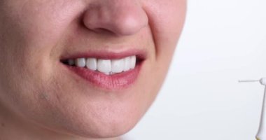 Geniş beyaz gülüşlü kadın, arka plandaki dişleri temizlemek için dişçi aletinin yanında duruyor. Sağlıklı dişleri olan bir kadın. Diş bakımı konsepti