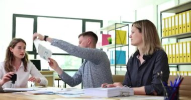 Erkek işçi, ahşap masada otururken damgalamak için meslektaşına kağıt belge verir. Yönetici ofis çalışanları patrona gayret ve sıkı çalışma gösteriyor