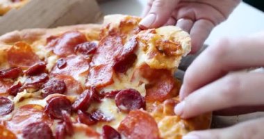 Kadın eli sıcak pizzadan bir parça koparır. Gıda teslimatı konsepti