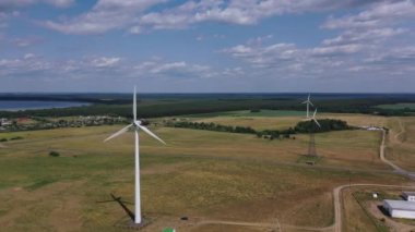 Tarlaların ve ormanların arka planına karşı elektrik türbinleri. Yenilenebilir ve çevre dostu enerji kavramı. 4k video filmi