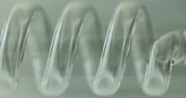 Beyaz arka planda spiral şeffaf plastik laboratuvar ekipmanı tüpü. Kimyasal reaktörü incelemek için küçük bir detay. Ayrı nesne
