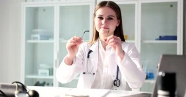 Steteskopta uzman bir uzman tıbbi tesiste randevu sırasında gözlük takıyor. Kadın doktor hastalarını ağır çekimde kabul eder.