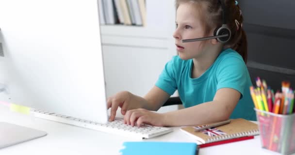 Pieni Tyttö Kuulokkeissa Kirjoittaa Tietokoneen Näppäimistöllä Katselee Elokuvaa Koulutus Verkossa — kuvapankkivideo