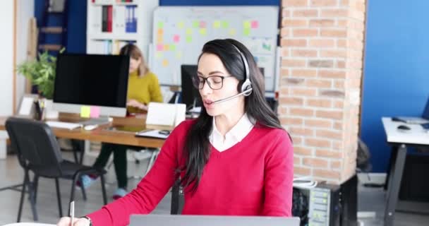 在工作单位的4K电影中 戴耳机对着话筒说话的女人 呼叫中心概念方面的工作 — 图库视频影像