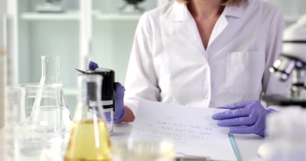 穿着橡胶手套的实验室工作人员在医疗摘要上贴上打印图以进行分析和签名 女科学家在文件中证实了有关研究的信息 — 图库视频影像