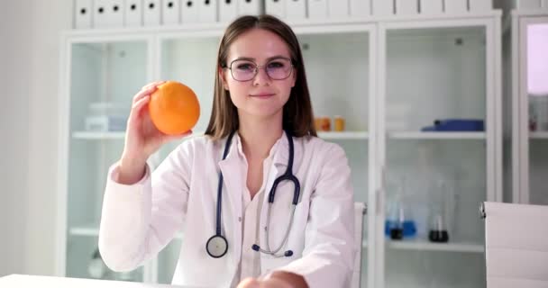 女性科学者は実験室で化学の専門知識の後にオレンジをお勧めします 専門家は遅い動きを親指を示す果物の承認を示しています — ストック動画