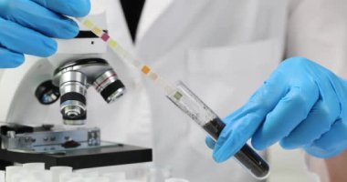 Bilim adamı cam test tüpündeki toprağa asit göstergesi yerleştirdi. Tıbbi tesis laboratuarında laboratuvar asistanı toprak asidite incelemesi yavaş çekim