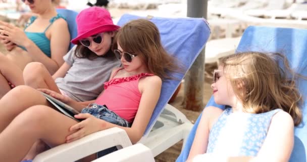 선글라스를 해변에서 일광욕을 즐기는 소녀들 태블릿으로 비디오 게임을 여학생들은 휴가를 — 비디오