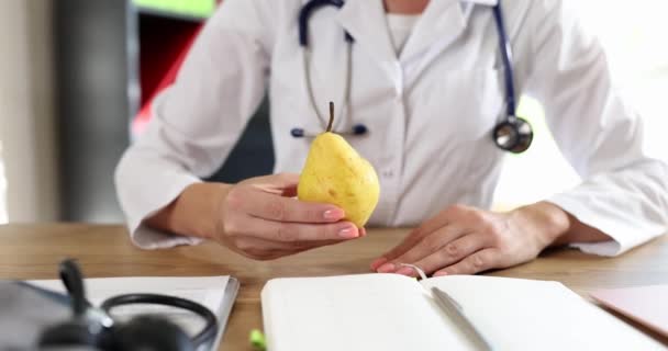 Female Doctor Gives Patient Fresh Pear Sitting Table Clinic Office — Stockvideo