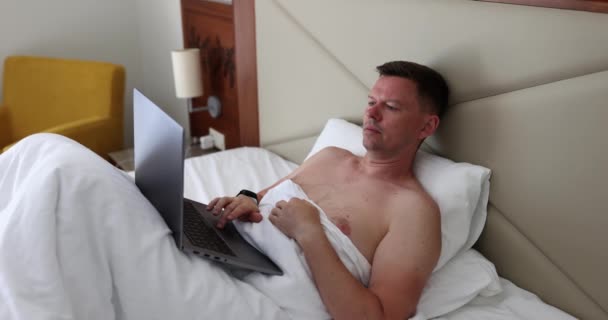 Male Freelancer Works Laptop Lying Bed White Blanket Hotel Room — Vídeos de Stock