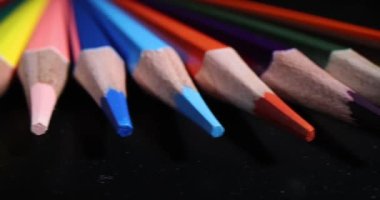 Sharpened multi-colored pencil tips lined up on black surface. Stationery made for kids and adults for drawing and studying purposes. Tool for artist