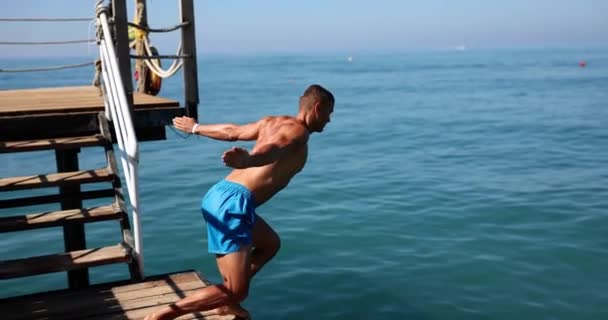 Ein Junger Athletischer Mann Taucht Von Einem Holzsteg Ins Meer — Stockvideo
