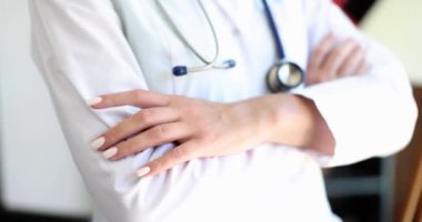Beyaz üniformalı doktor ellerini çaprazladı, yakın plan, yavaş çekim. Tıp uzmanı, meslek.