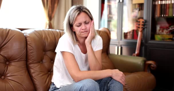 ソファの上の家に座っている女性は 彼女の顔 クローズアップ スローモーションをストロークします 顎の痛み — ストック動画