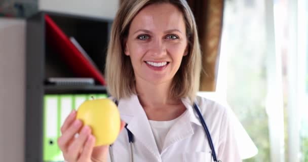 Smiling Woman Doctor Clinic Holds Yellow Apple Close Visit Nutritionist — Stock Video