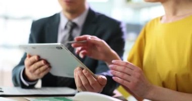 İki iş ortağı tablet bilgisayarda gösterilen bilgileri tartışıyor. Erkek ve kadın ofis çalışmasında ekranı işaret ediyor