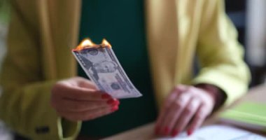 Ofiste oturan bir kadın dolar yakıyor, yakın plan, yavaş çekim. Sahte faturalar, para arzının azaltılması.