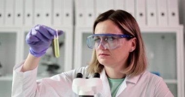 Bilim adamı laboratuarda ham petrol ve petrol ürünleriyle test tüplerini inceliyor. Biyologlar ışık ve koyu sıvıyla test tüpleri tutuyor.
