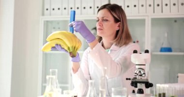 Bilim adamı elinde muz testi yapar ve laboratuvarın önünde oturur. Meyvedeki gıda kalitesi ve toksin konsepti üzerine araştırma
