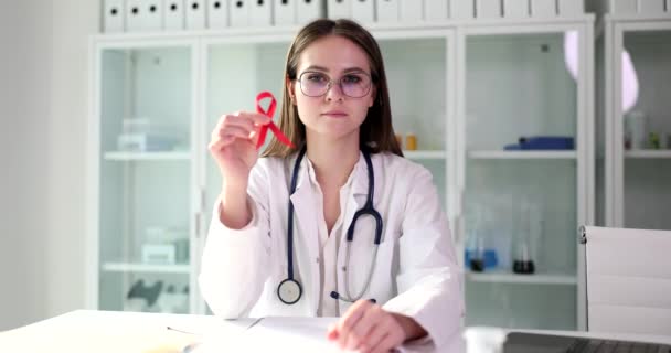 医師はエイズのシンボルとして病院で赤いリボンを保持しています 国際エイズデーとHiv意識 — ストック動画