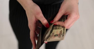 Kadın ellerinin çantadaki dolarları sayması. Cüzdanından 50 dolarlık bir banknot çıkar ve hizmetlerin ve malların parasını öde.