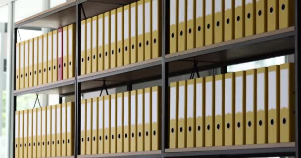 Czerwony Folder Biznesowy Przesuwa Się Rzędach Identycznych Żółtych Folderów Półce — Wideo stockowe
