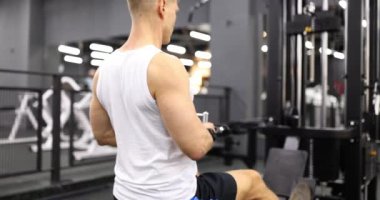Erkek vücut geliştirme trenleri spor salonunda simülatörde ağırlık kaldırıyor. Spor salonunda egzersiz yapan bir sporcu.