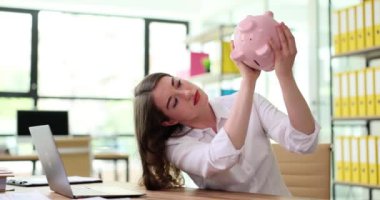 Kadın yönetici elinde pembe kumbarayı sallıyor. Bankacılık ve tasarruf kavramı