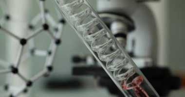 Laboratuvarda, spiral tüp içinde akan şeffaf kırmızı sıvının yakın çekimi. Zehirli sıvılar üzerine çalışmalar