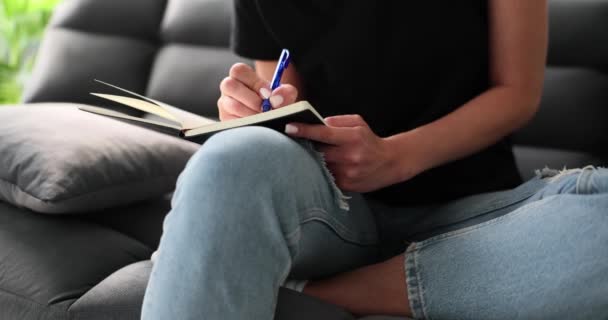 Μια Γυναίκα Κάθεται Στον Καναπέ Και Γράφει Κάτι Στο Σημειωματάριο — Αρχείο Βίντεο