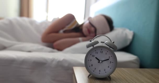 ブランケットでベッドに横たわる子供のティーンエイジャーは 朝10時に自信を持って警報時計を鳴らします 睡眠マスクで寝る — ストック動画