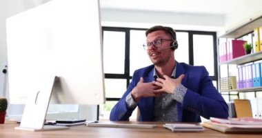 Kablosuz kulaklık takmış gülümseyen bir iş adamı bilgisayar ekranına bakarak konferans videosu çekiyor. Mutlu satıcı müşteri hizmetleri