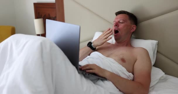 Schöner Mann Bett Unter Der Decke Mit Laptop Gähnt Armer — Stockvideo