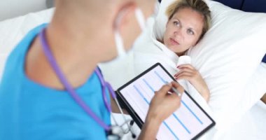 Doktor hasta hastanın yanında oturup dijital tablet 4K filminde şikâyetler yazıyor. Ev sağlığı konsepti