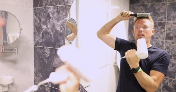 Jovem Penteando Frente Espelho Soprando Suas Bochechas Com Secador Cabelo — Vídeo de Stock