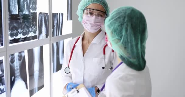 Orvosok Védőszemüveget Védőmaszkot Viselnek Miközben Röntgenfelvételeket Nézegetnek Klinikán Egészségügyi Személyzet — Stock videók
