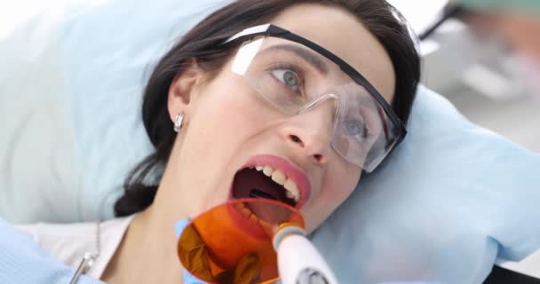 Tandläkare Som Behandlar Tänder Till Kvinnliga Patienter Med Hjälp Kureringsljus — Stockvideo
