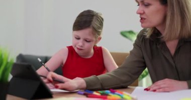 Eğitimli anne ve çocuğun ödevlerine yardım etmek masa başında oturup çizim yapmak. Öğretmek ve öğrenmek ve küçük kızla anne olmak.