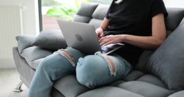 Dizüstü bilgisayarı olan bir kadın evde koltukta oturuyor. Uzak çalışma ve serbest çalışma