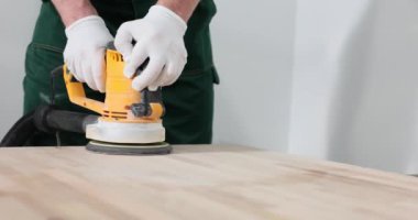 Marangoz odasındaki öğütücüyle ahşap tahtanın yüzeyini parlatır. İnşaatçı inşaat malzemeleri hazırlar.