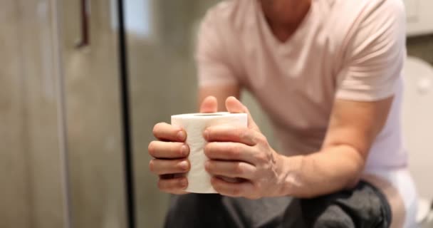 男はトイレに座ってティッシュペーパーを持っている 健康問題コンセプト — ストック動画