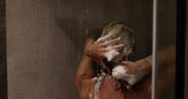 Genç bir kadın saçlarını duşta yıkıyor. Saç bakımı