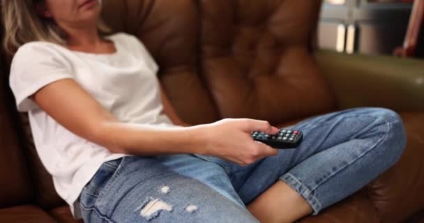 Müde Frau Sitzt Auf Der Couch Und Schaltet Mit Fernbedienung — Stockvideo