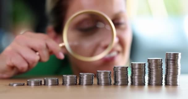 女商人用放大镜按升序检查成堆的硬币 财政利润和现金收入的增长 — 图库视频影像